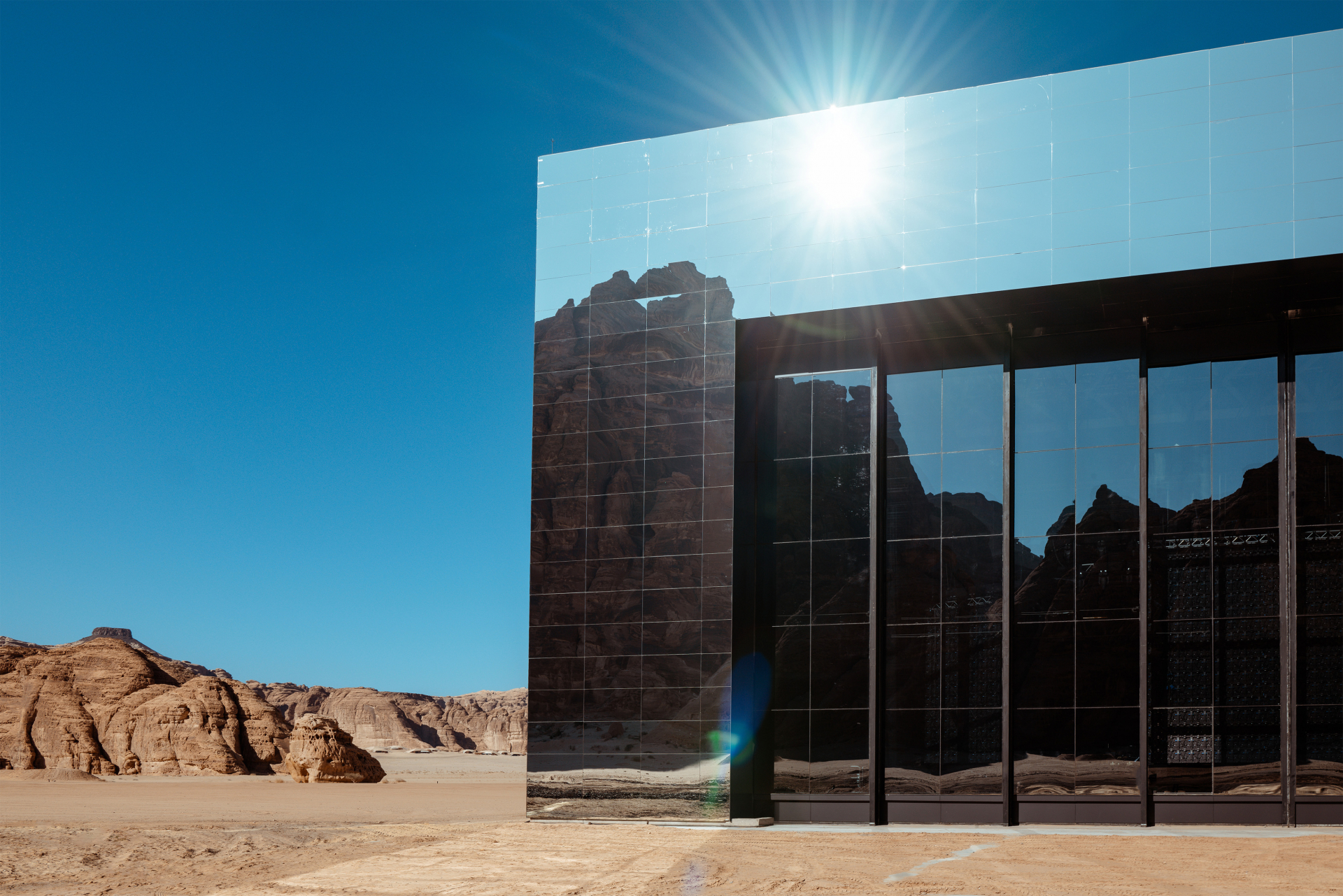 Spiegelverkleidetes Gebäude der Maraya Concert Hall glänzt in der Sonne vor felsiger Kulisse                                                                                            